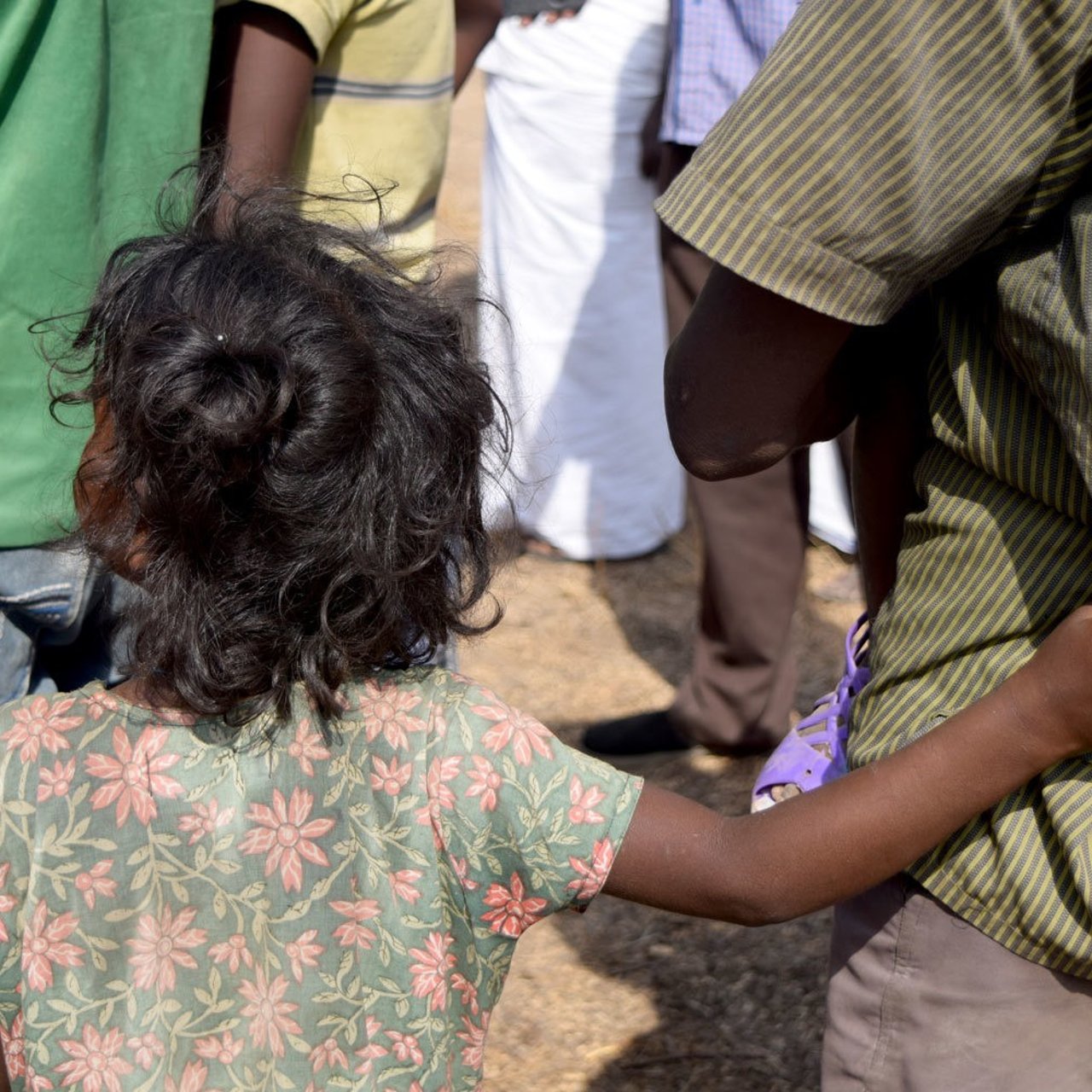 A child holding on to her father during enquiry